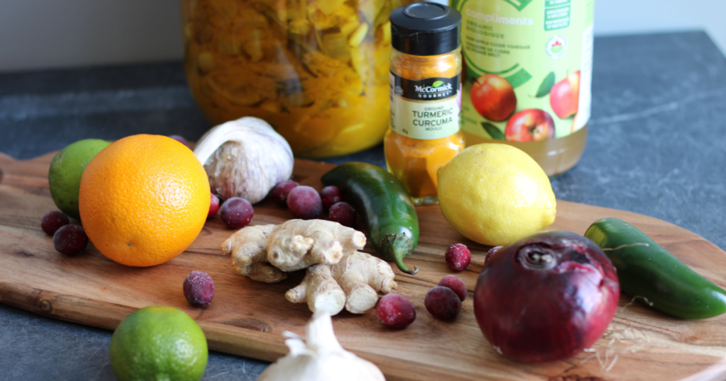Cutting boards with oranges, limes, lemons, garlic, ginger, cranberries, red onion and jalapenos.