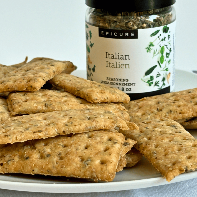 A plate of sourdough discard crackers with a jar of Epicure Italian seasoning.