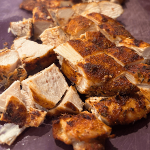 Cut up cooked Cajun seasoned chicken breast on a cutting board.