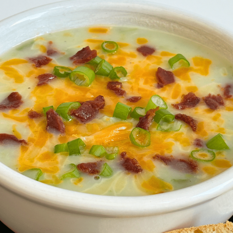 Bowl of creamy potato soup topped with cheese, bacon bits and green onions.