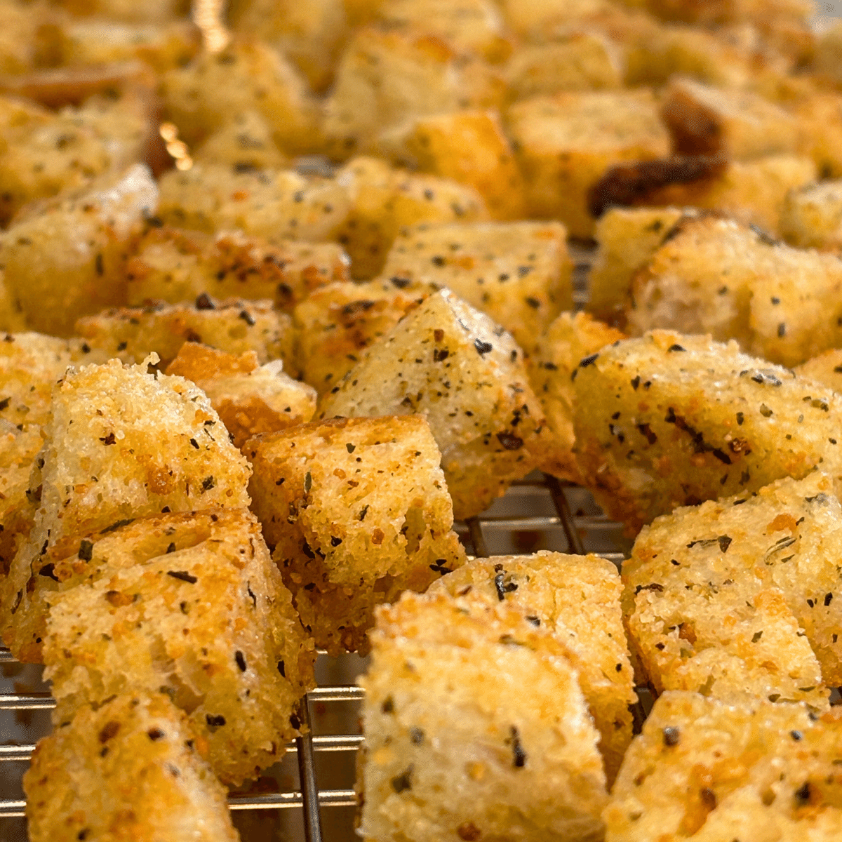 Close up of Italian seasoned sourdough croutons on a cooking rack.