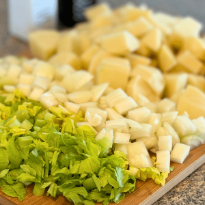 Cutting board with diced potatoes, onions and celery.