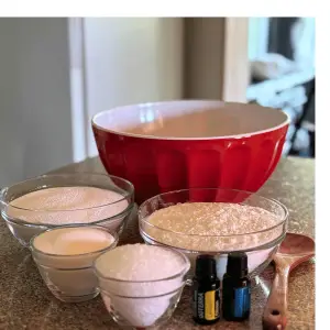 Big red bowl, wooden spoon and bowls of ingredients needed to make homemade non-toxic laundry detergent. 