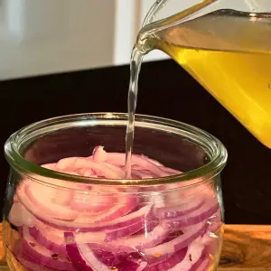 Brine pouring over sliced red onions