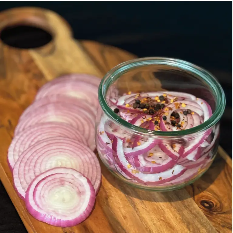 Sliced red onion on a cutting board and in a wreck jar.