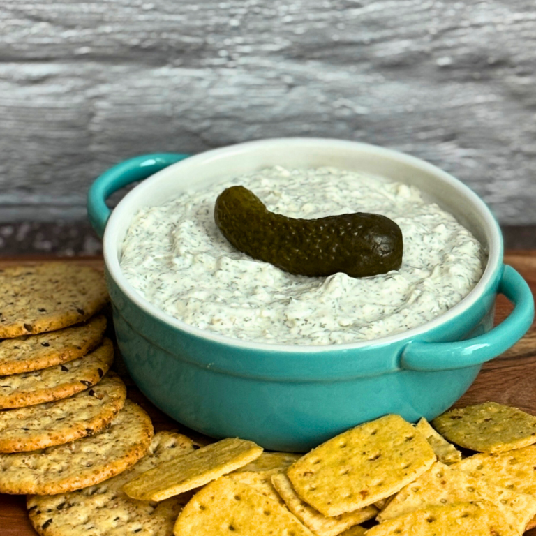 Dill pickle dip in a dish surrounded by crackers.