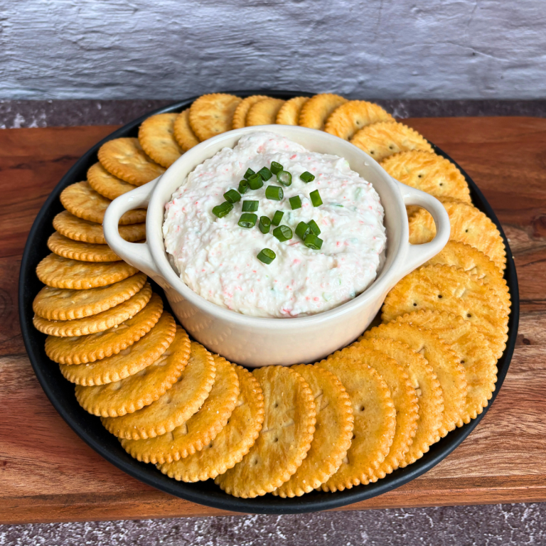 bowl of crab dip surrounded by Ritz crackers