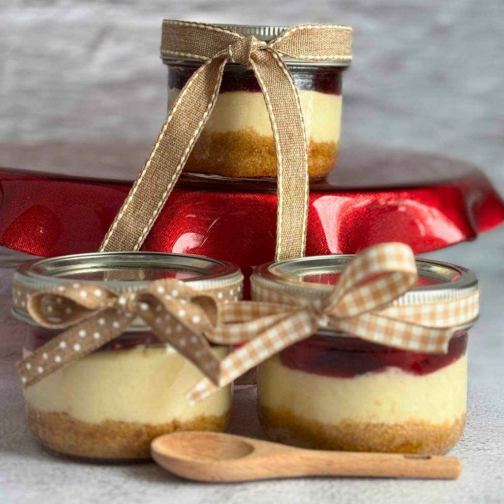 Three cheesecake in a jar with decorative ribbon.