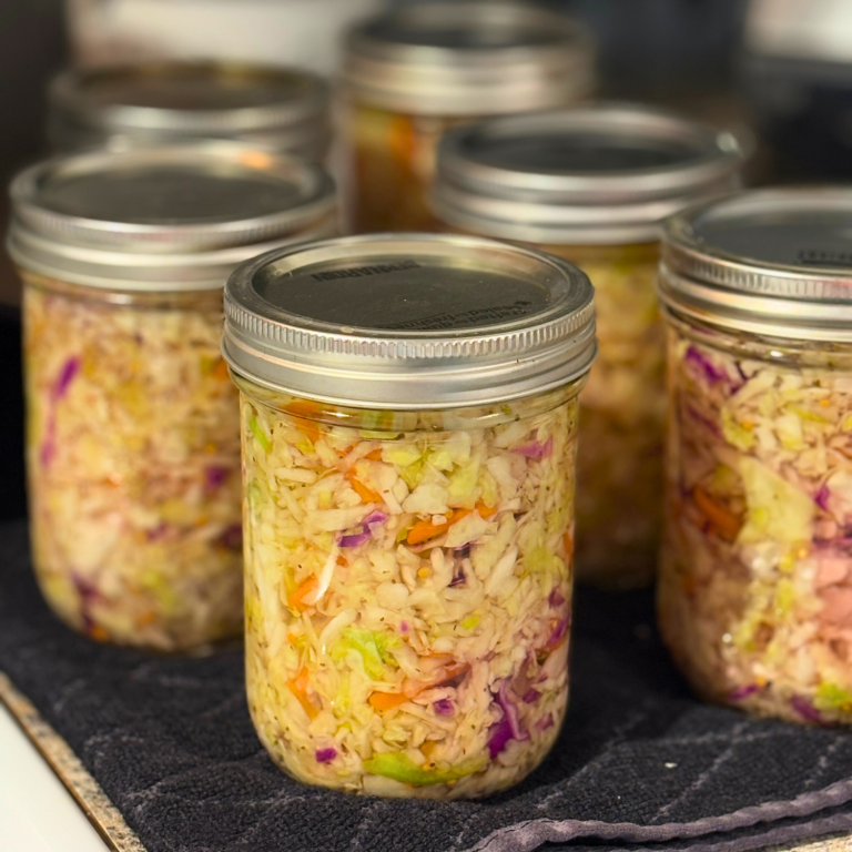 Jars of canned coleslaw on a black towel.