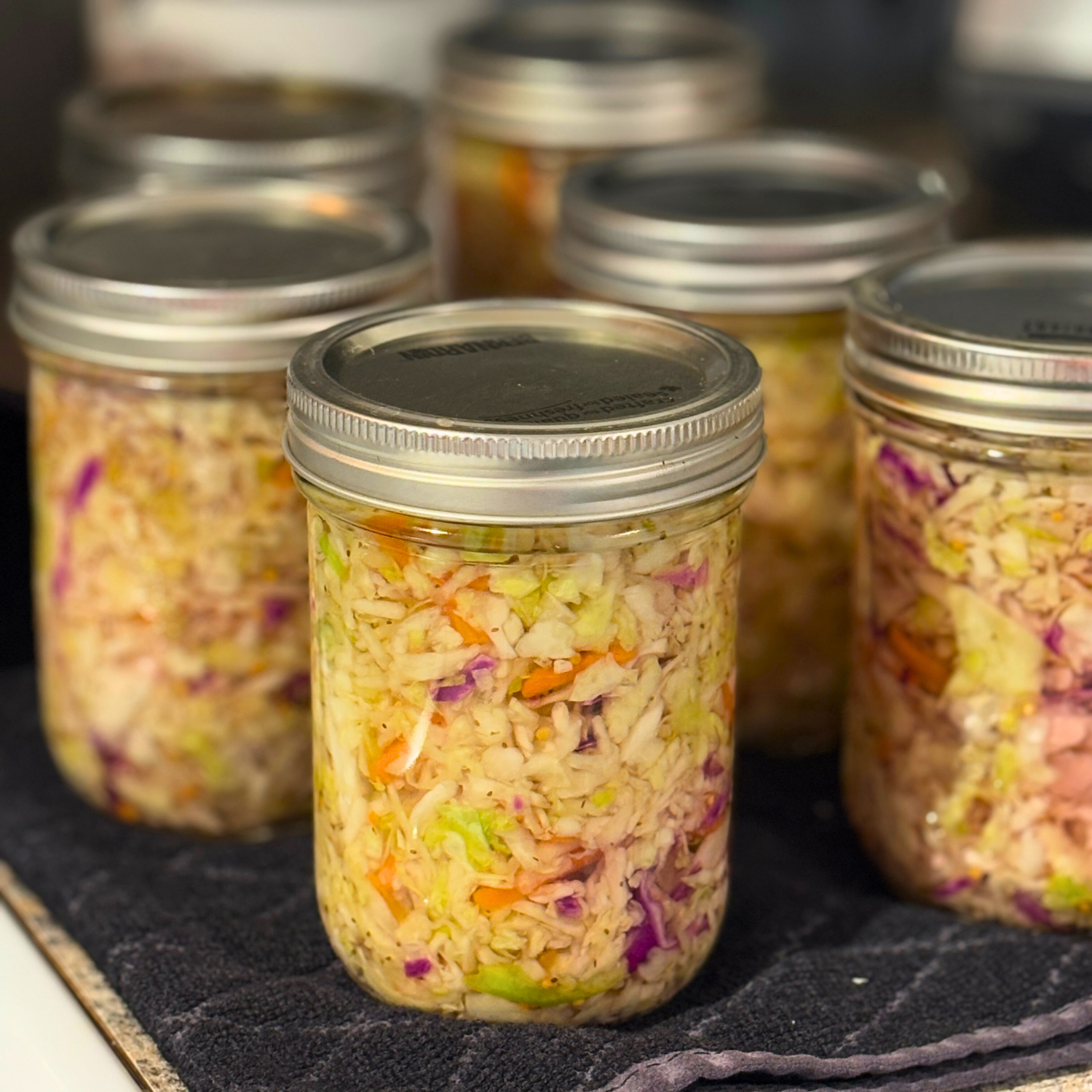 Jars of canned coleslaw on a black towel.