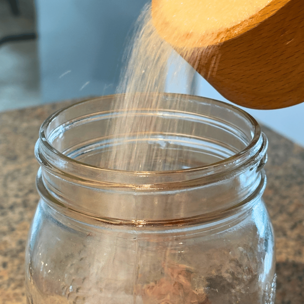 Sugar pouring into a quart jar.