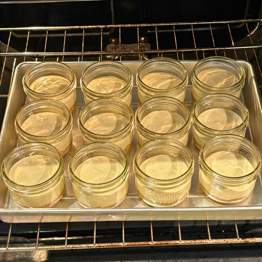 Cheesecake in a jar in a baking dish going into the oven