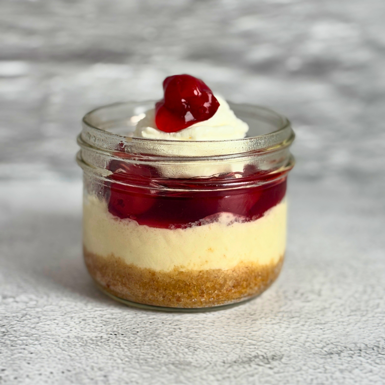 Cheesecake topped with whipped topping in a mason jar.