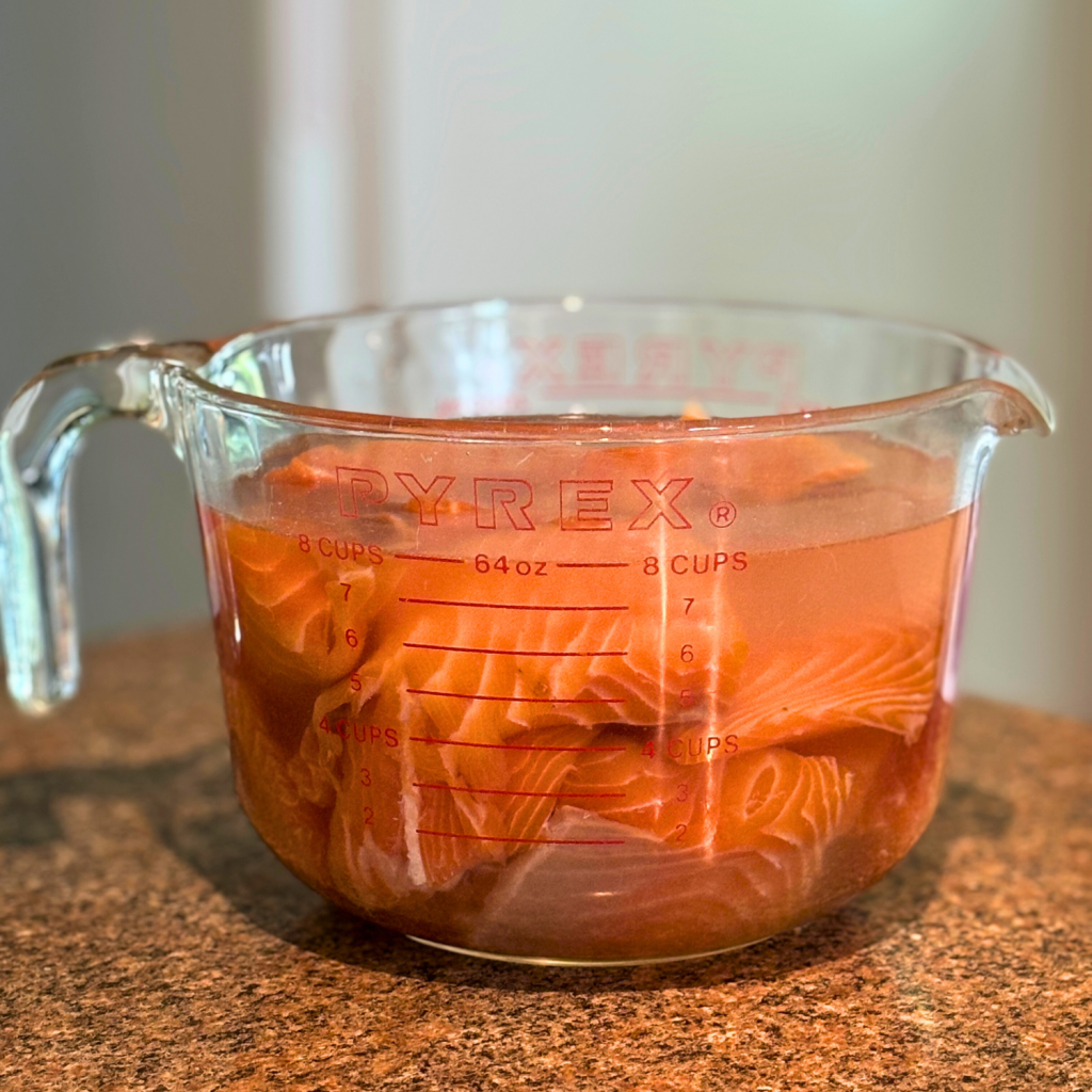 Salmon pieces soaking in a salt water brine.
