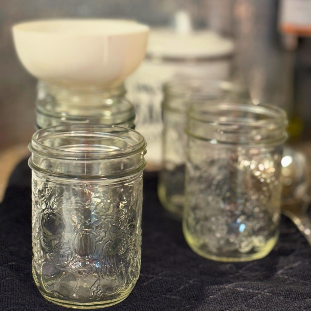 Empty canning pint jar and one has a canning funnel in it.