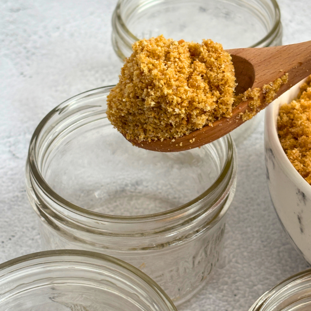 Empty mason jar with spoon full of graham cracker crust mixture.