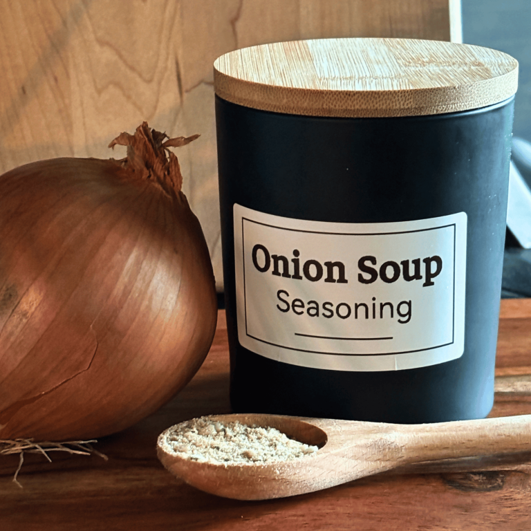 DIY Onion soup mix container with bamboo lid with a spoon containing the dried onion soup mix and a large onion next to the jar.