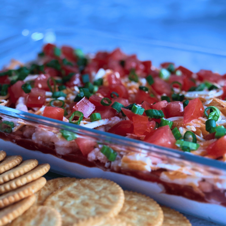 Layered Crab and Green onion dip next to Ritz crackers.
