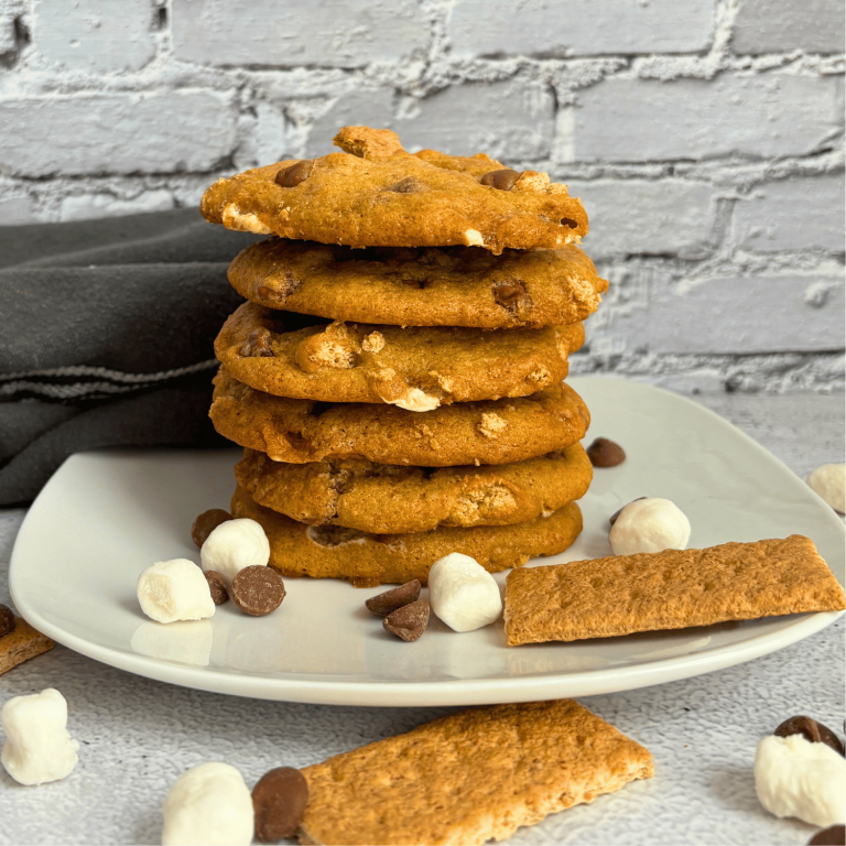 Stack of Sourdough Discard Smores cookies on a plate surrounded by graham crackers, chocolate chips and mini marshmallows