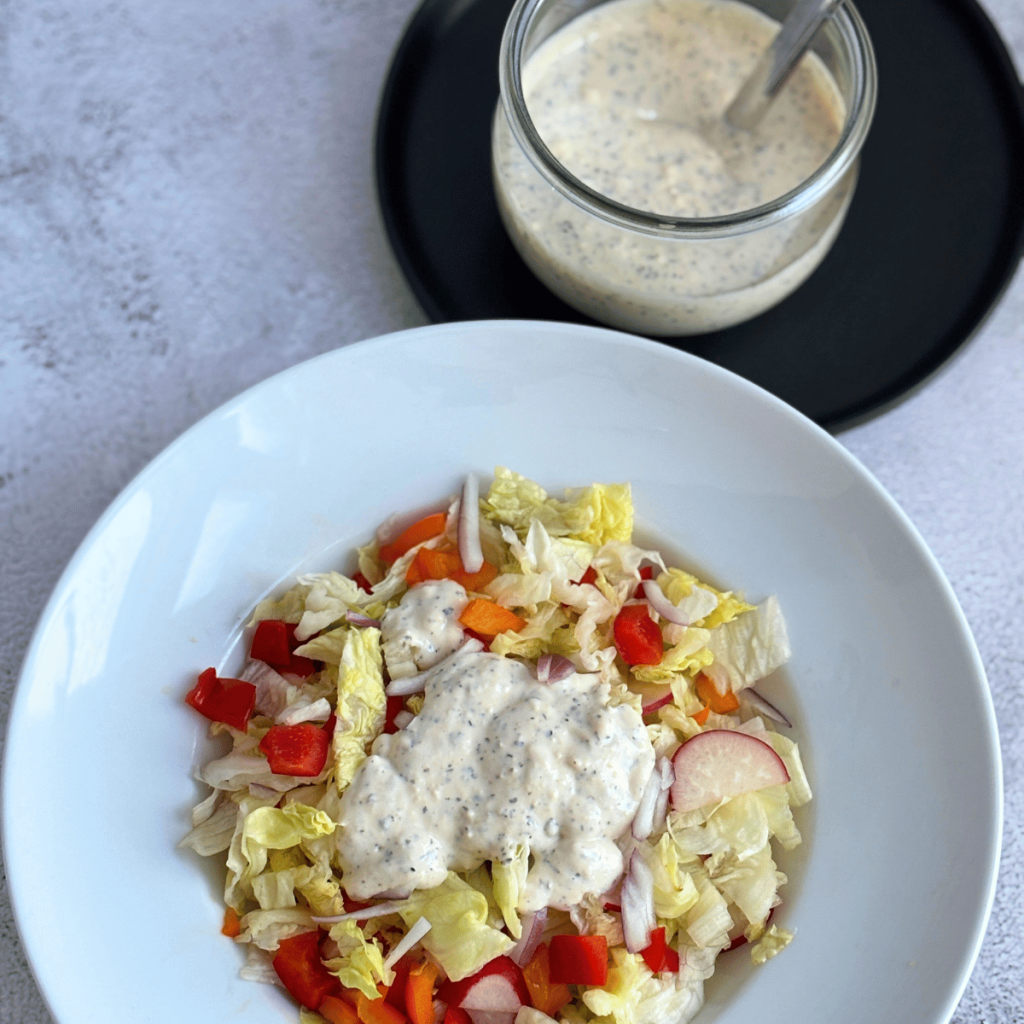 Green salad with Creamy Italian Dressing and a Weck jar with dressing in the background.
