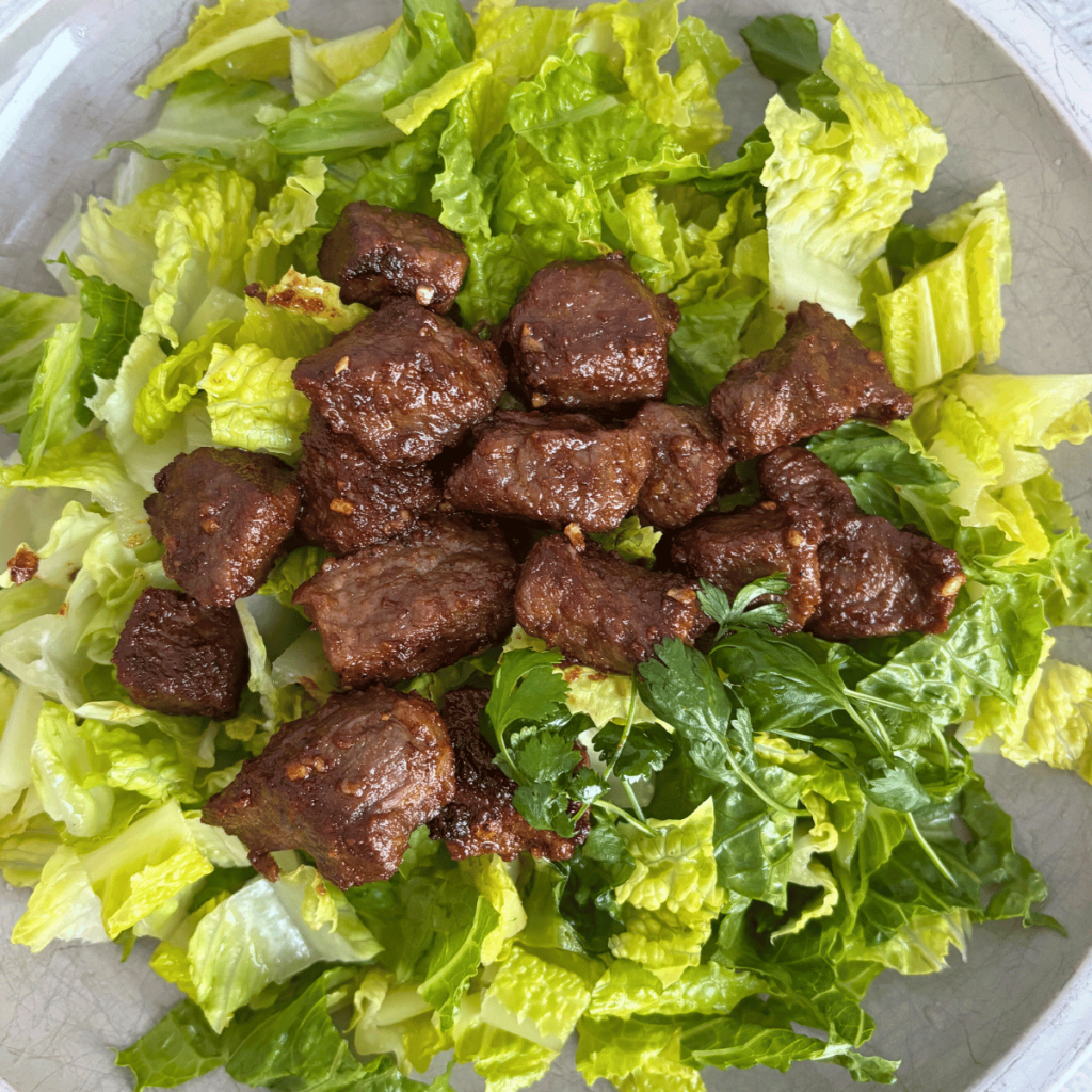Steak bites on a bed of lettuce.
