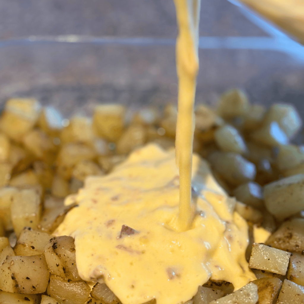 Pouring egg mixture over roasted potatoes.