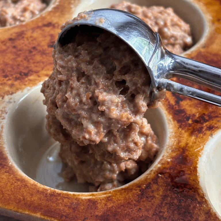 Refrigerator bran muffin batter in a large cookie scoop dumping into a stone muffin pan.