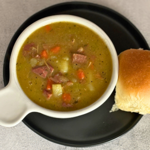 Bowl of ham and potato stew with a homemade bun on the side