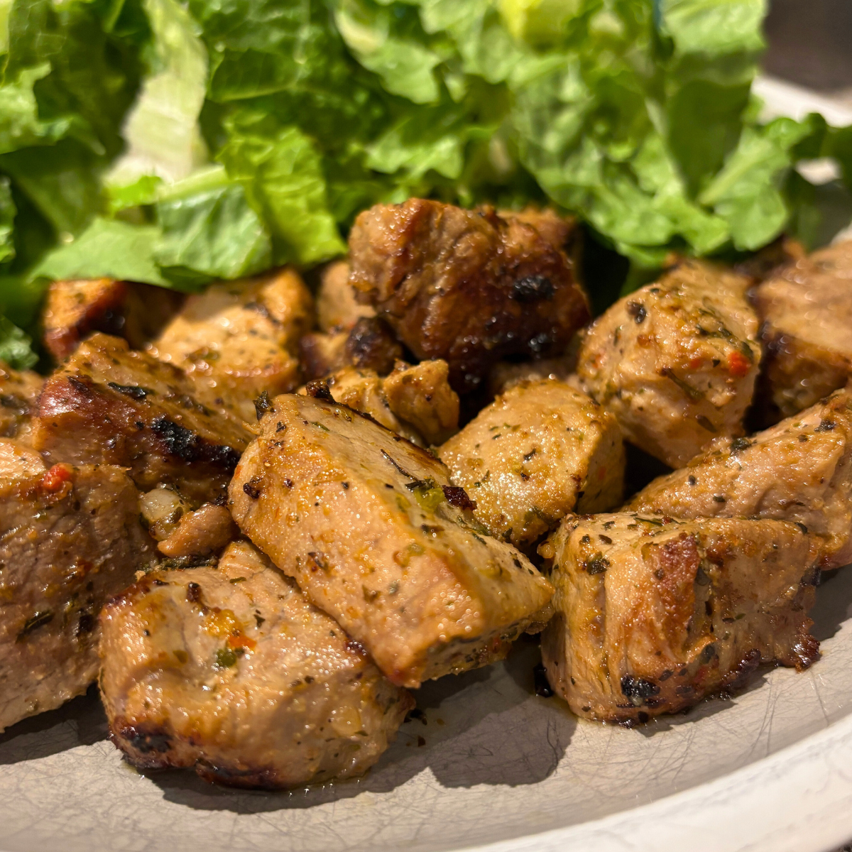 Greek Souvlaki pieces on a plate next to some salad.