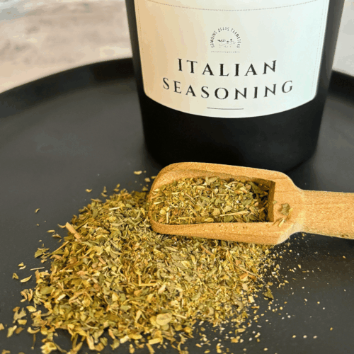 Italian Seasoning in a wooden scoop on a black plate